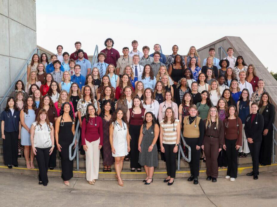 Large group of students and instructors posing together on outdoor steps.