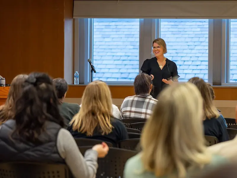 A woman speaks to an audience from the front of a lecture room.