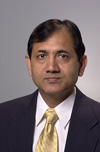 A professional headshot of a man wearing a suit and tie.