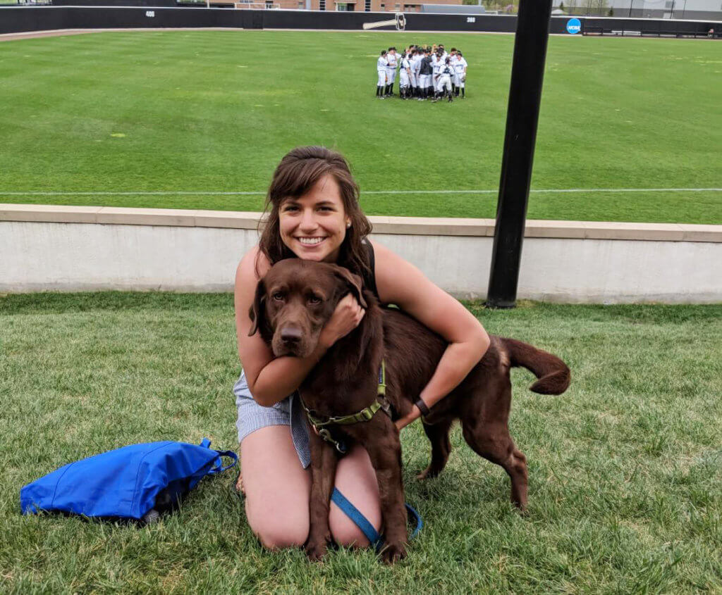 Kayla pictured with her dog, Rallo, in the grass at a Purdue baseball game