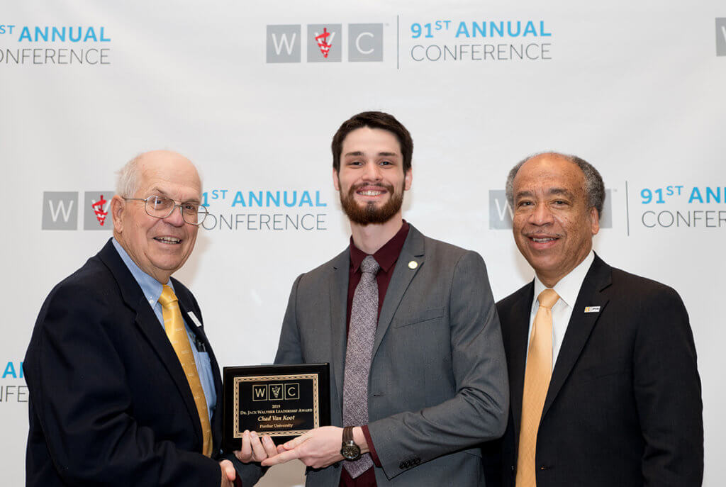 Chad Van Koot holds award plaque with WVC president and Dean Reed