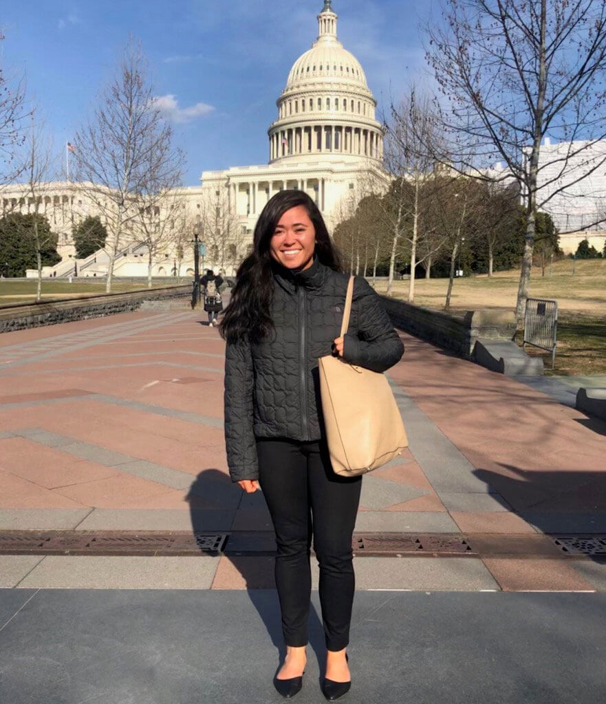 Kristi Crow stands on the sidewalk with the US Capitol Building in the background