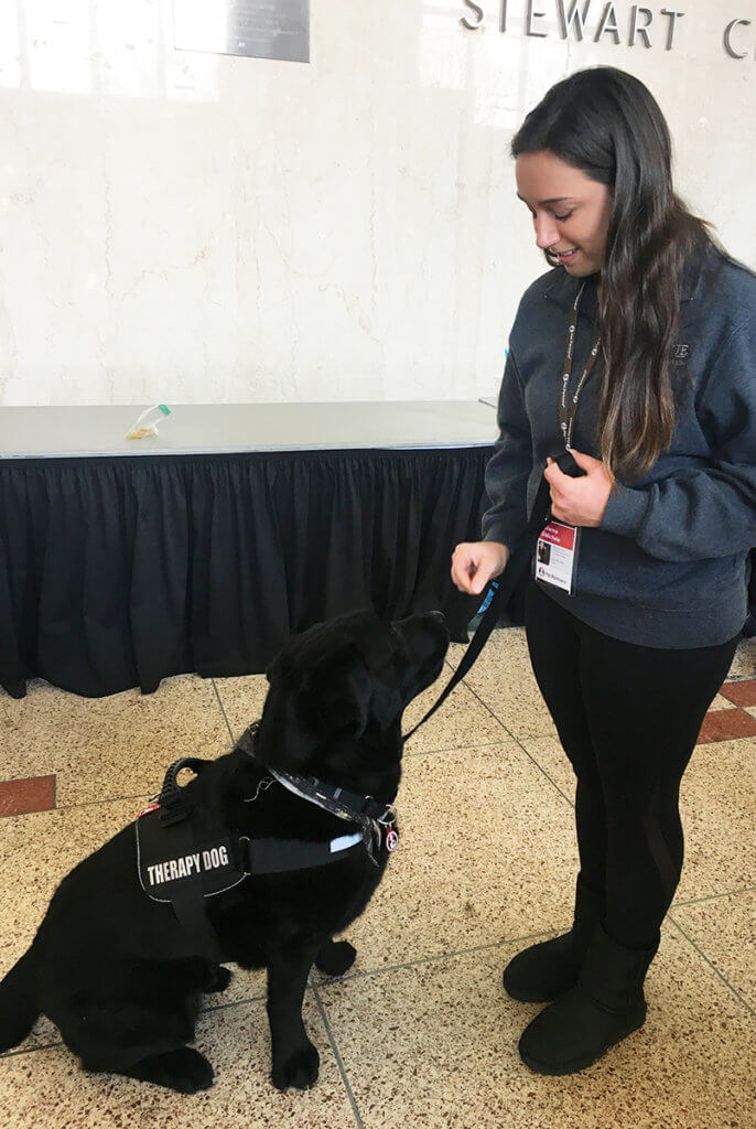 Frankie the dog receives a treat from Julianna in Stewart Center