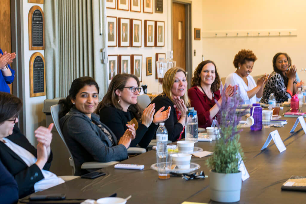 Femail faculty members clap as they're seated around a table