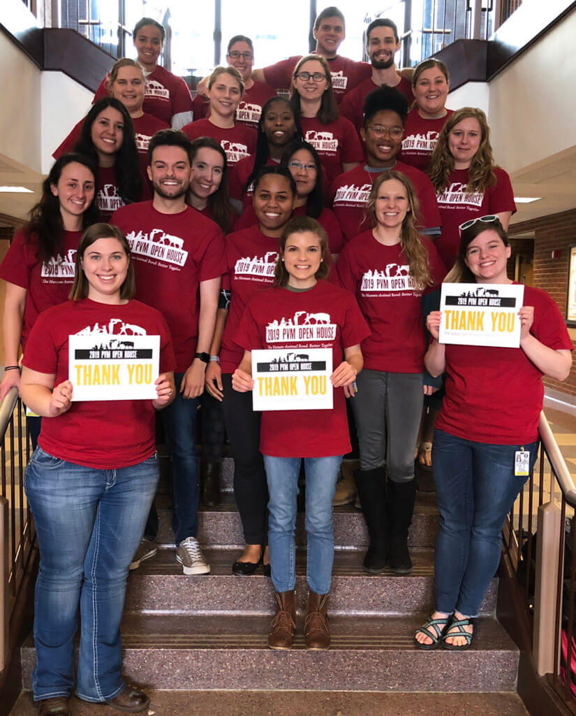 Students who served on the Open House Committe stand on a staircase holding thank you signs