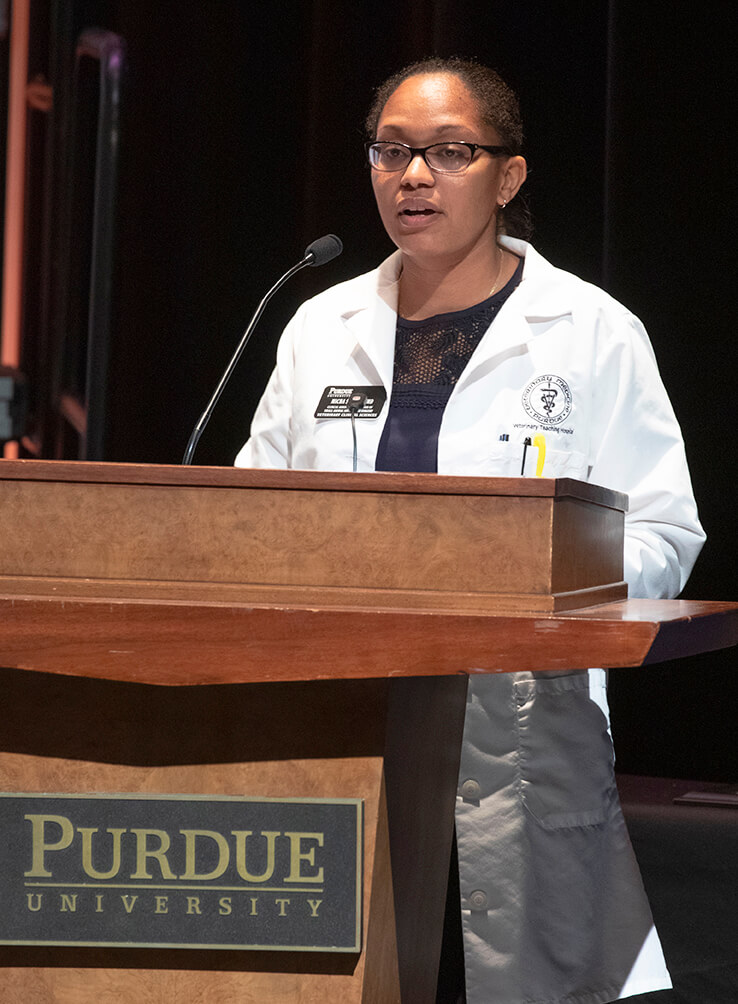 Dr. Micha Simons speaks on stage behind a podium