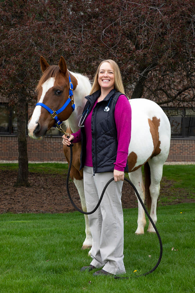 Sandy Taylor holds the harness of a painted horse outside