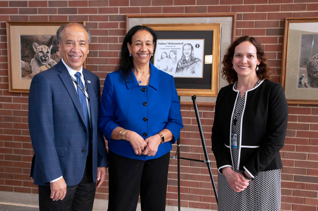 Dean Reed stands with Sulma Mohamed and Kenitra Hendrix with Sulma's illustration displayed in the background