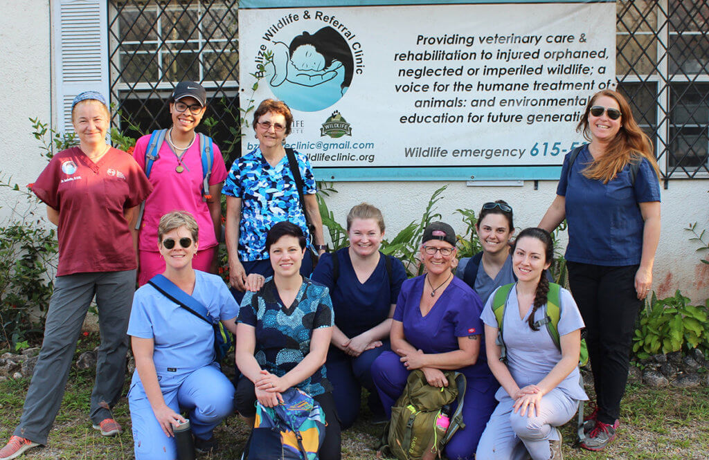 Participants pause for a group photo in front of the Belize Wildlife and Referral Clinic's sign with clinic co-founder, Dr. Paquet-Durand