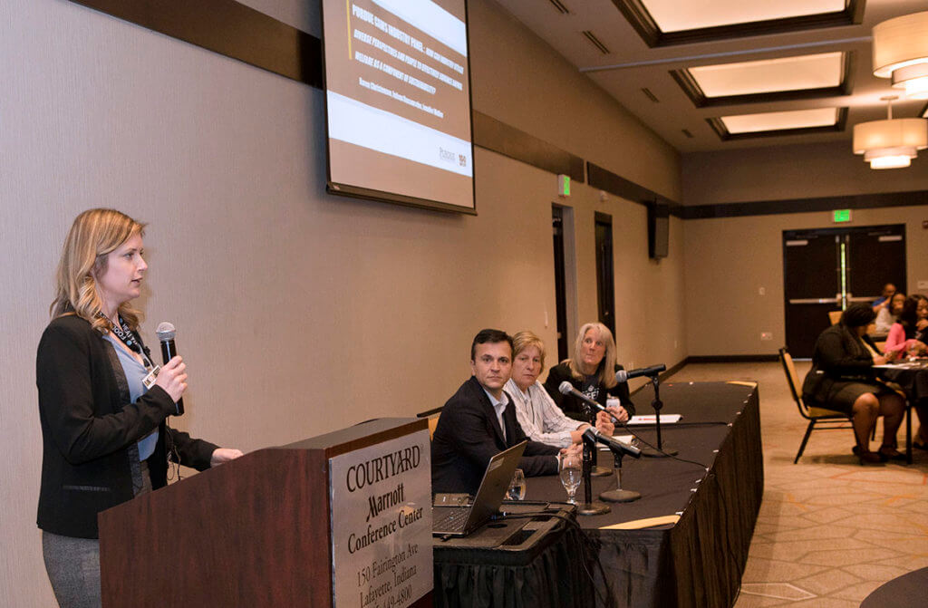 Industry experts sit as a panel in front of symposium attendees