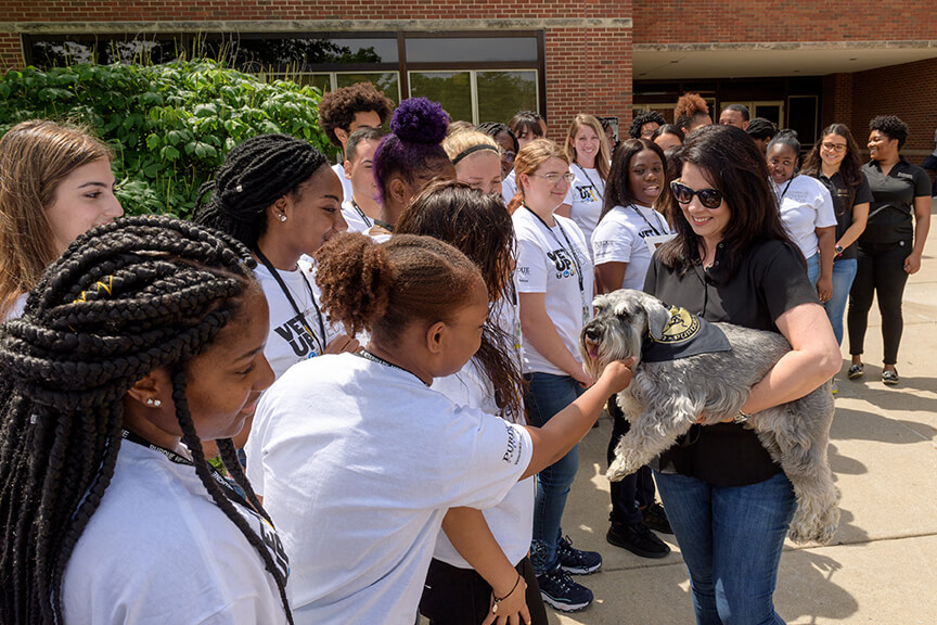 students greet Henry held by Janet Holcombas they meet outside Lynn Hall