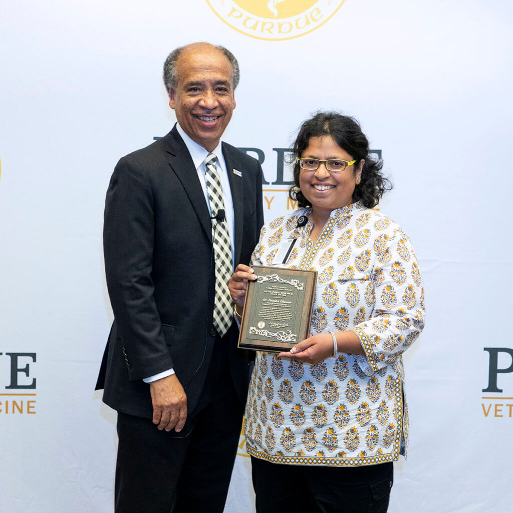 Deepika stands with Dean Reed holding her award plaque