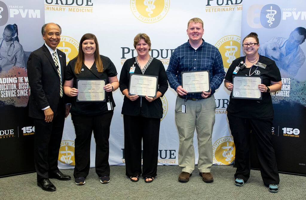 staff and faculty recognized for completing the online diversity certificate program stand with the dean holding their certificates of completion