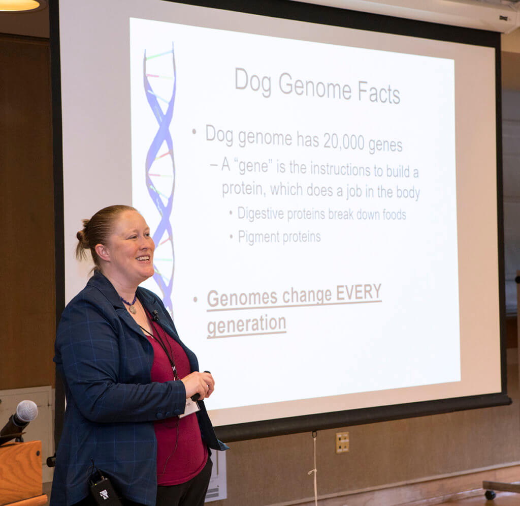 Dr. Ekenstedt stands beside a podium with her presentation displayed beside her at the Canine Welfare Science Forum