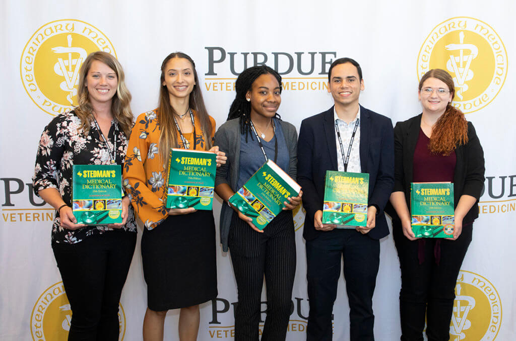 Outstanding Vet Up! College participants hold up their Stedman's Medical Dictionary books in front of the PVM logo banner