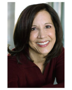 A close-up portrait of a smiling woman with shoulder-length dark hair, wearing a red top.