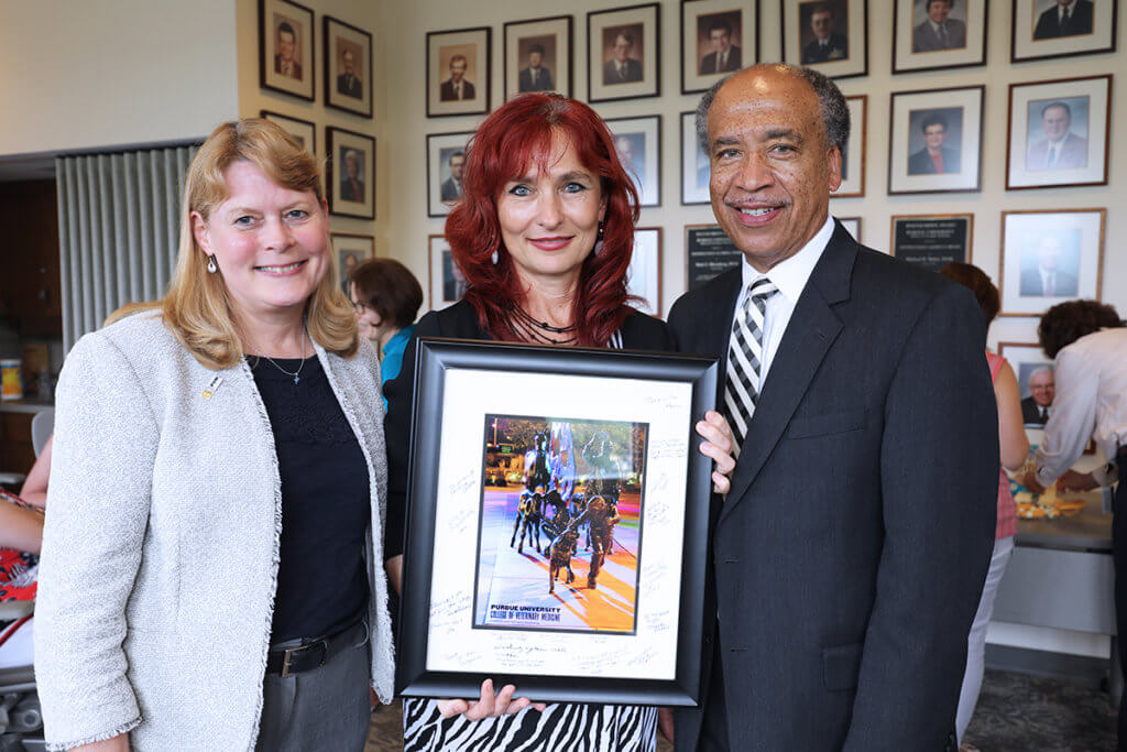 Dr. Nan holds a framed photo of the Continuum sculpture with Dr. Salisbury and Dean Reed by her side