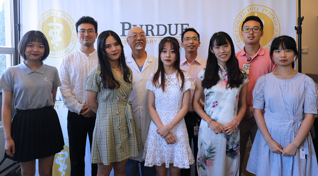 Sichuan Agricultural University students and a faculty member join Dr. Ko for a group picture in front of the PVM logo banner