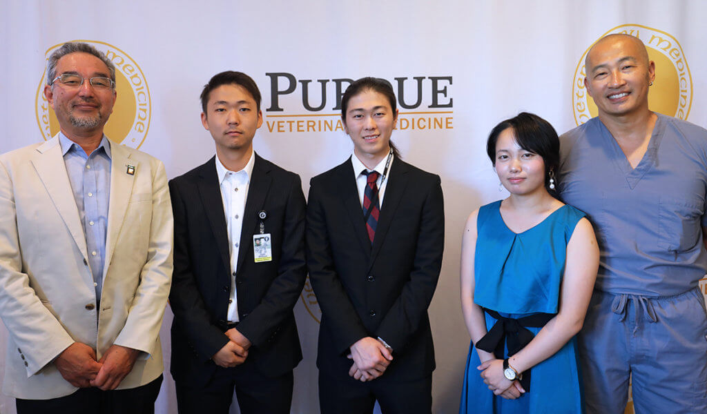 Rakuno Gakuen faculty and students are joined by Dr. Inoue for a group photo in front of the PVM logo banner