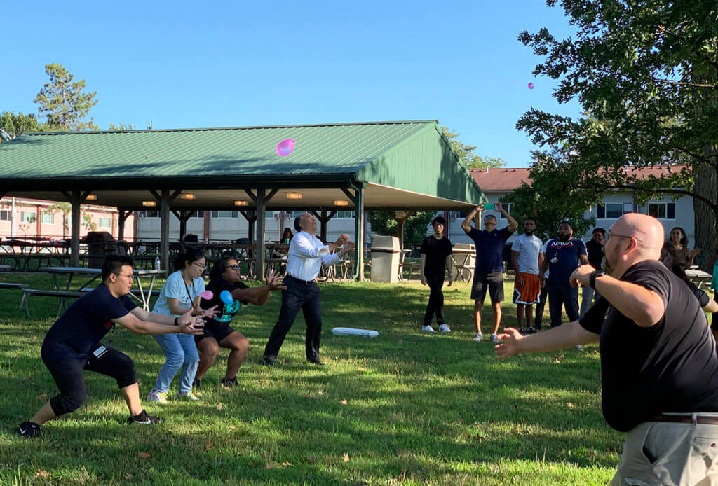 Kitasato students and veterinary medicine faculty and staff play water balloon toss outside in a park