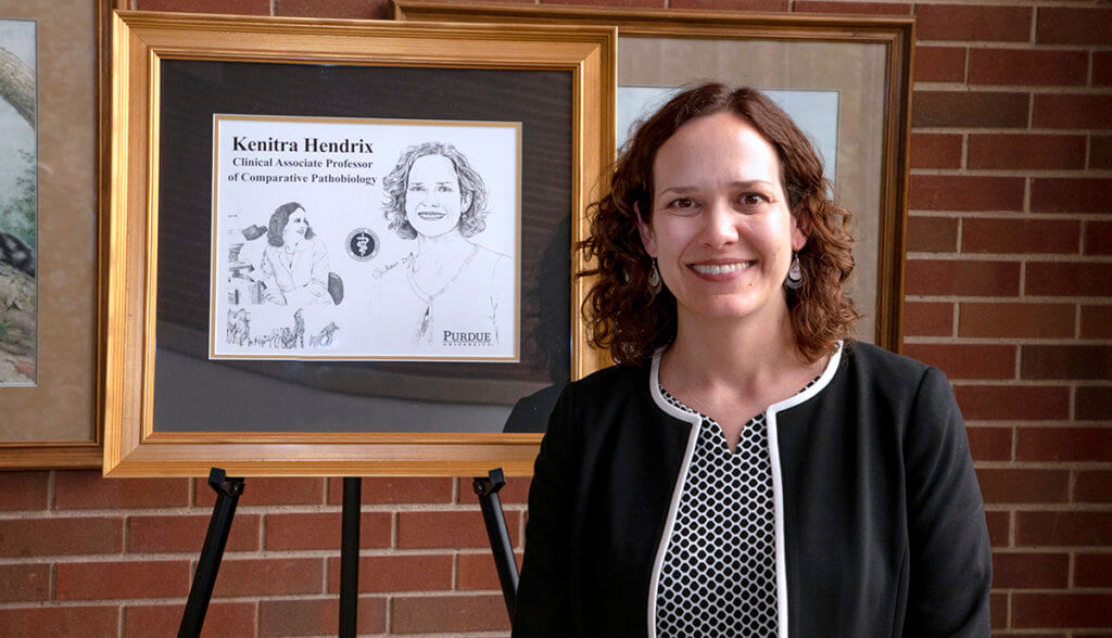 Dr. Hendrix stands beside a framed illustration of her in the Continuum Cafe