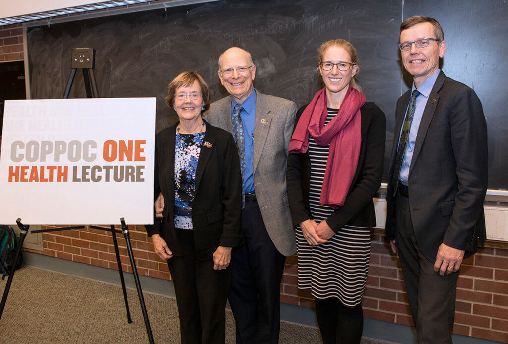 Dr. Coppoc and Harriet stand beside Dr. Plowright and Dr. HogenEsch alongside a sign that reads Coppoc One Health Lecture