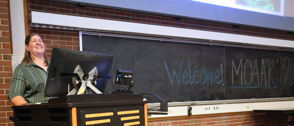 Dr. Field speaks to the crowd behind a podium in Lynn 1136