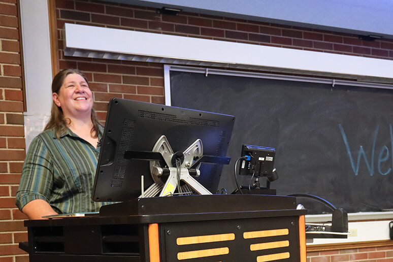 Dr. Field speaks to the crowd behind a podium in Lynn 1136