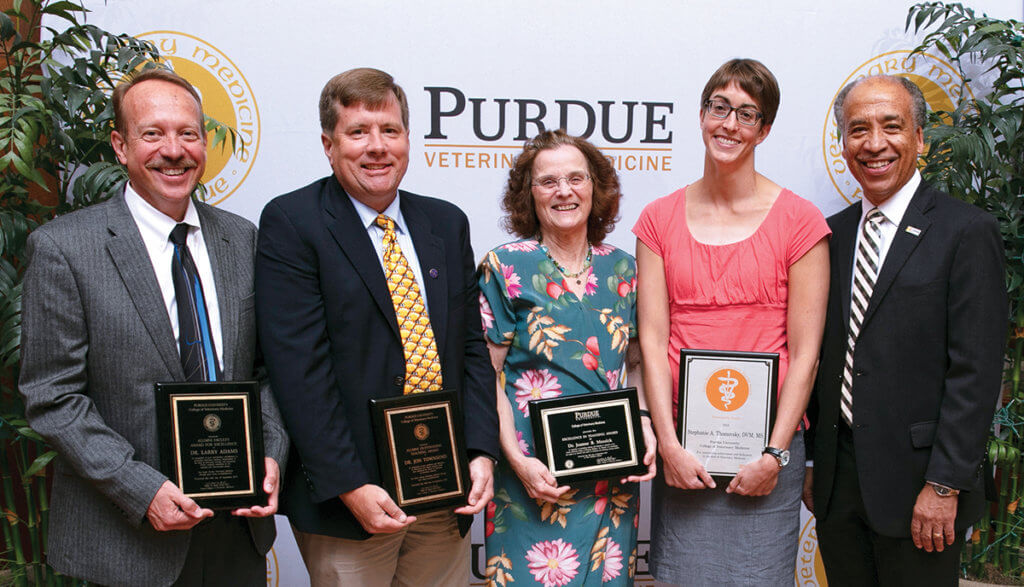 The faculty award winners stand together with Dean Reed holding their award plaques