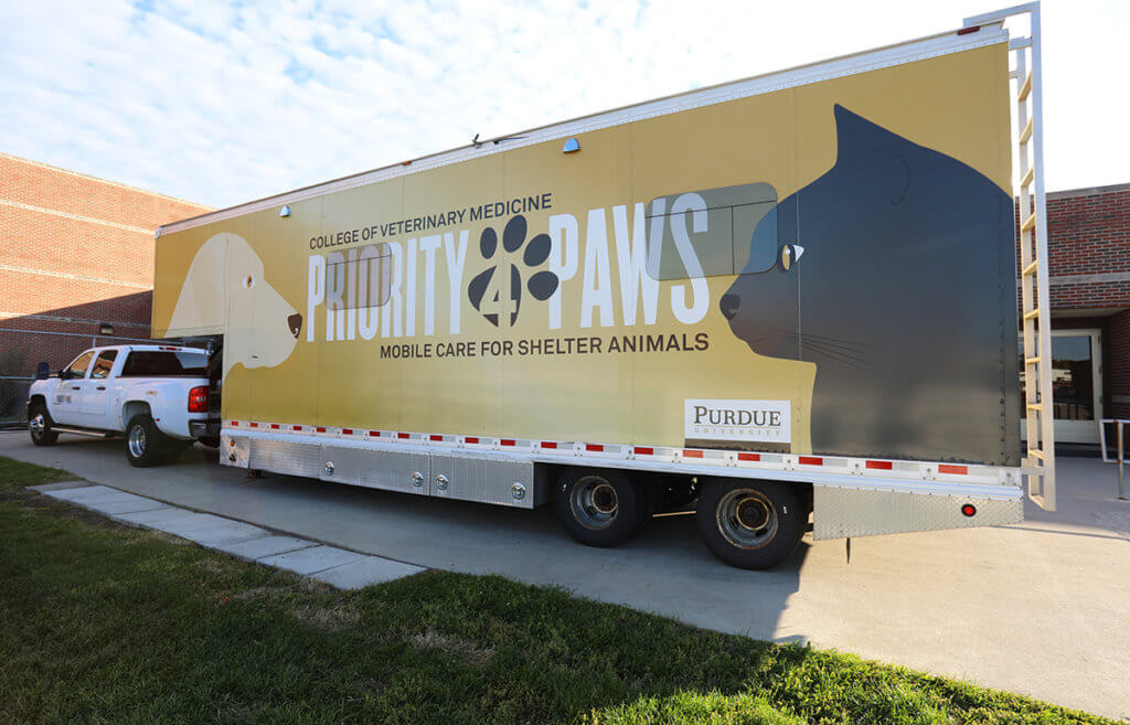 The Priority 4 Paws mobile surgery unit sits parked out the Purdue Veterinary Teaching Hospital against a blue cloud filled sky