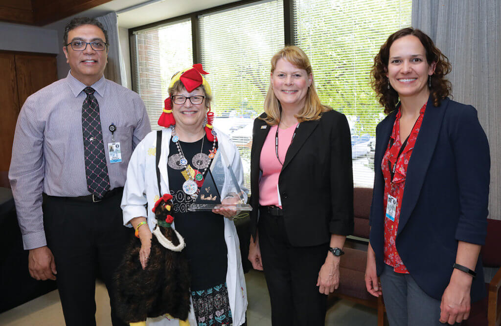 Dr. Narayanan, Dr. Salisbury, and Dr. Hendrix join Dr. Wakenell who is dressed in a poultry decorated hat and shirt as well as a poultry themed purse