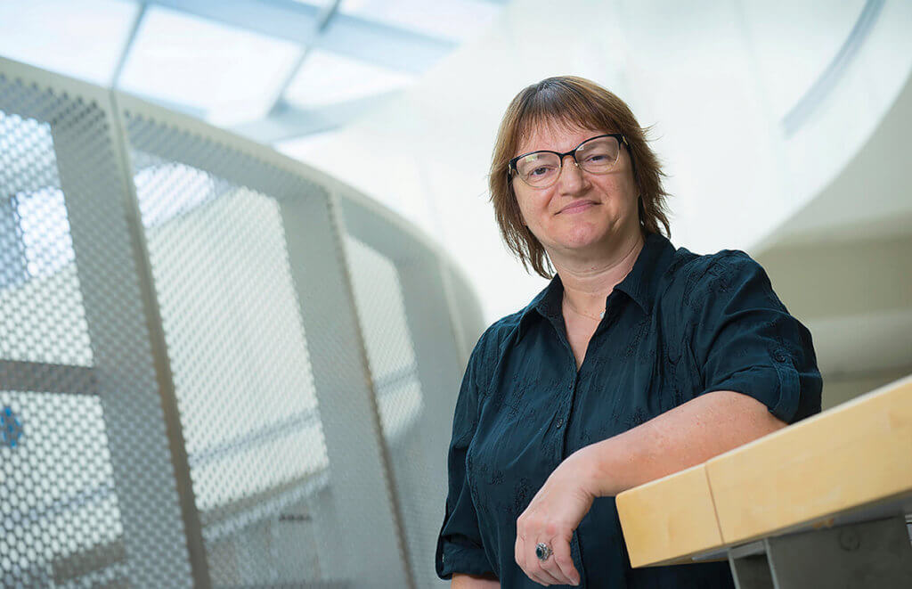 Dr. Lelievre leans against a stair rail smiling at the camera