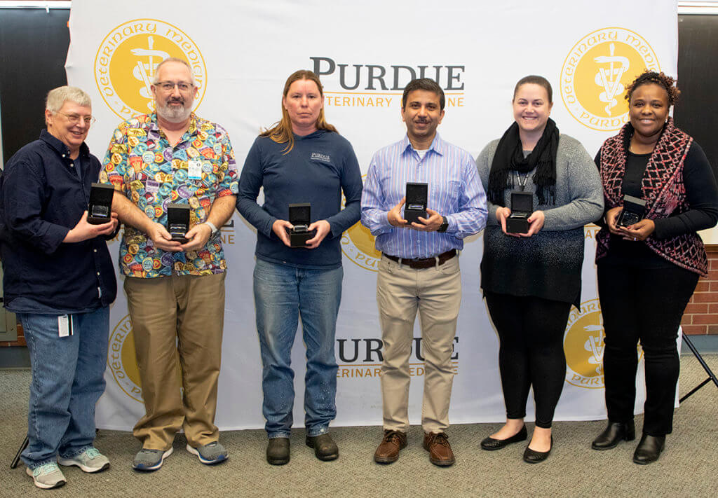 staff celebrating 10 years of service stand together with holding their commemorative gifts