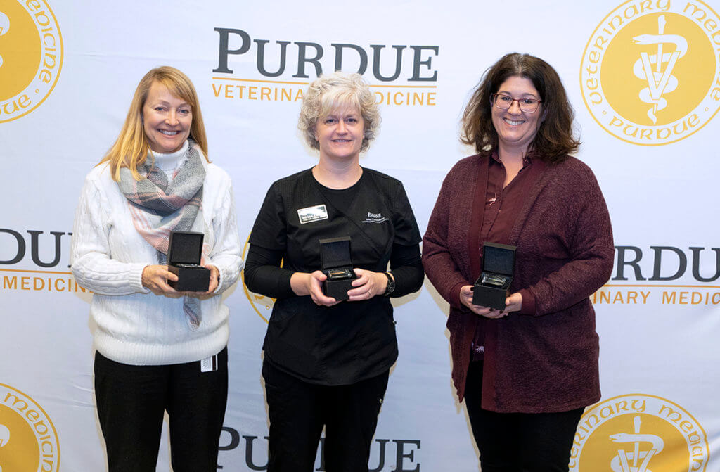 Staff members hold a commemorative gift for 15 years of service to the university