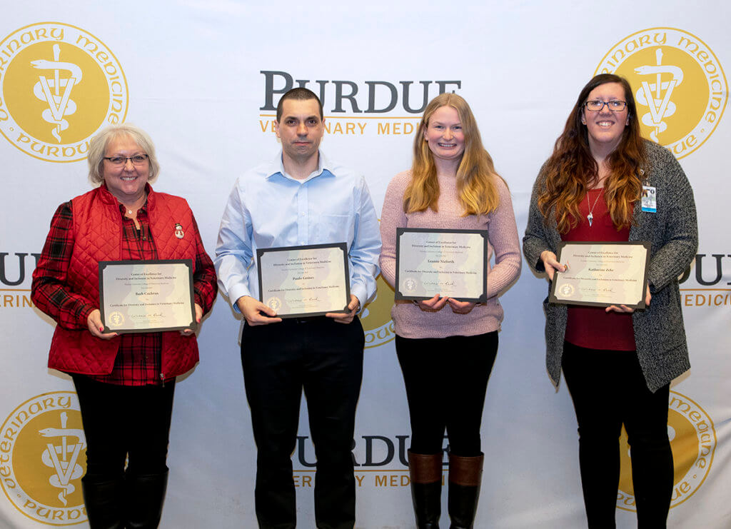 Certificate recipients stand together holding their certificates of completion