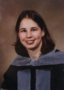 A portrait of a woman wearing academic regalia, smiling at the camera.