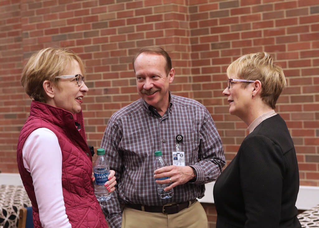 Dr. Lowery speaks with Dr. Laurie Adams and Dr. Larry Adams in the library