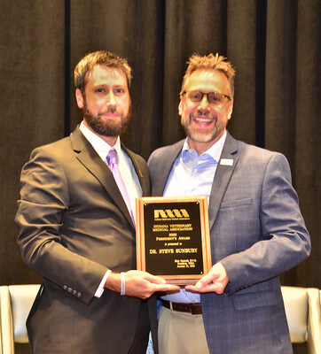 Matt and Steve stand together holding Steve's award plaque