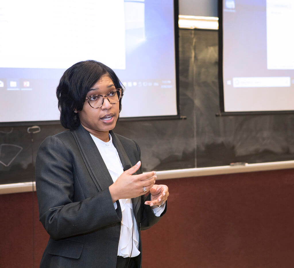 Dr. Craig speaks with her presentation displayed in the background