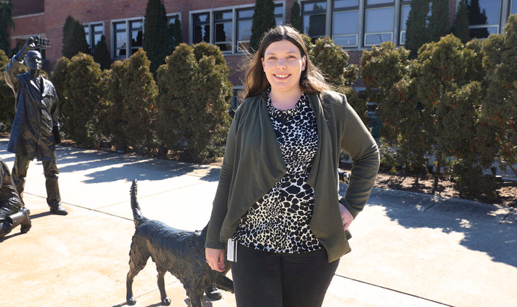 Shelbie stands outside Lynn Hall in front of the Continuum sculpture