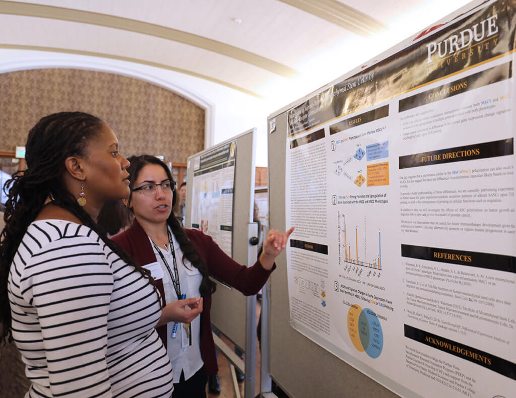 Cosette points to her research poster as speaks to Dr. Lyle