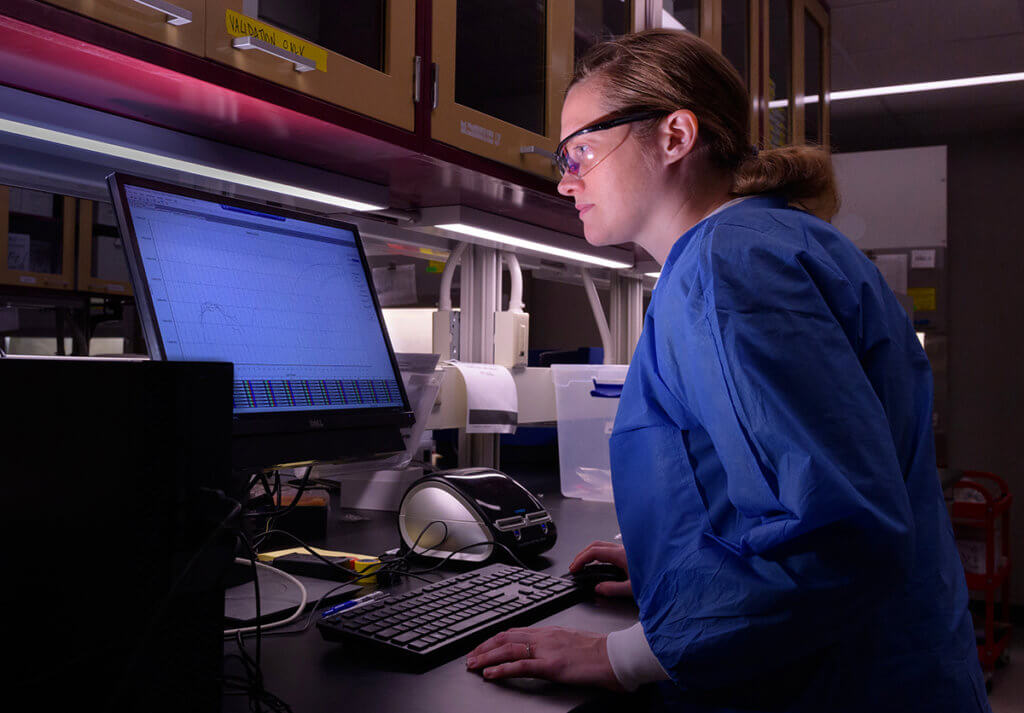 Angie looks over data on a computer monitor in the lab