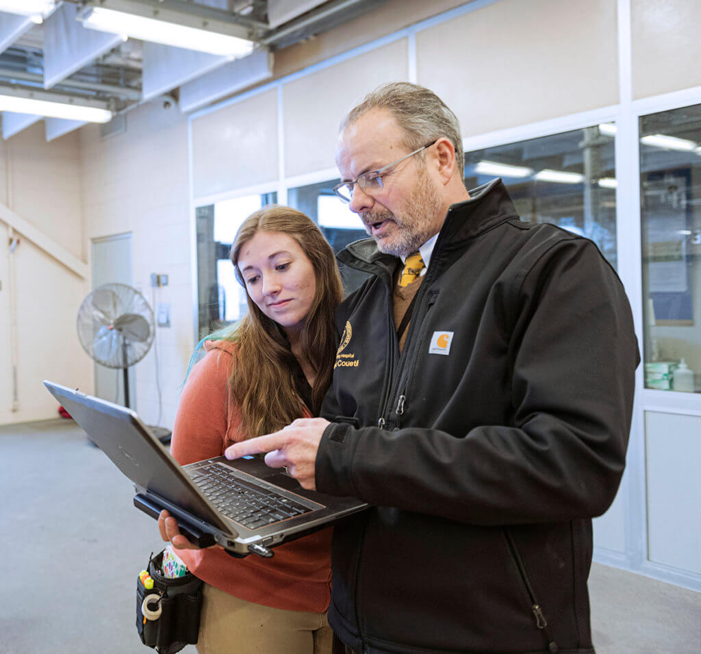 Dr. Couetil points to his laptop screen as a student looks on