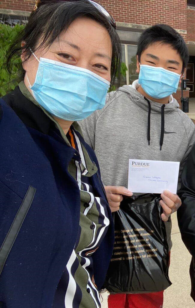 Johnny holds up an envelope as his mom snaps a photo of them