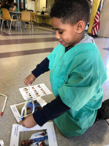 A young child dressed in scrubs is focused on playing with educational materials related to healthcare.