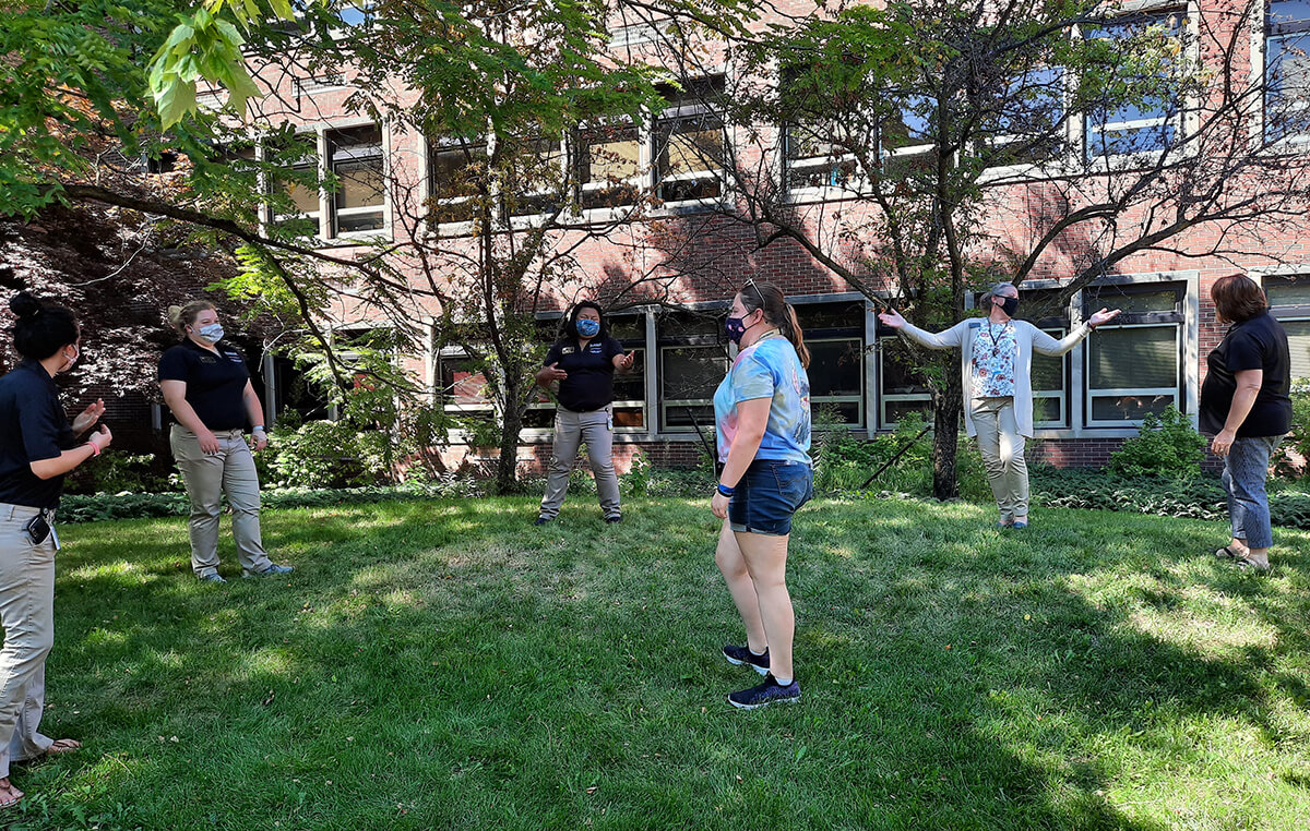 Students and staff stand socially distanced in the grass