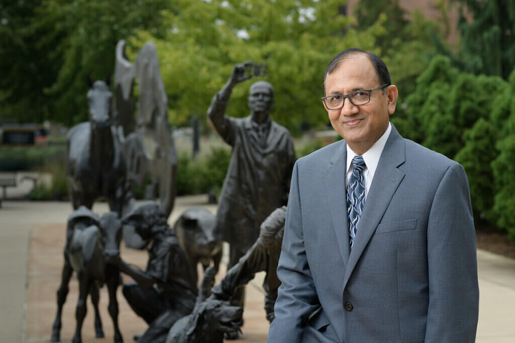 Suresh Mittal pictured standing in front of the Continuum sculpture outside Lynn Hall