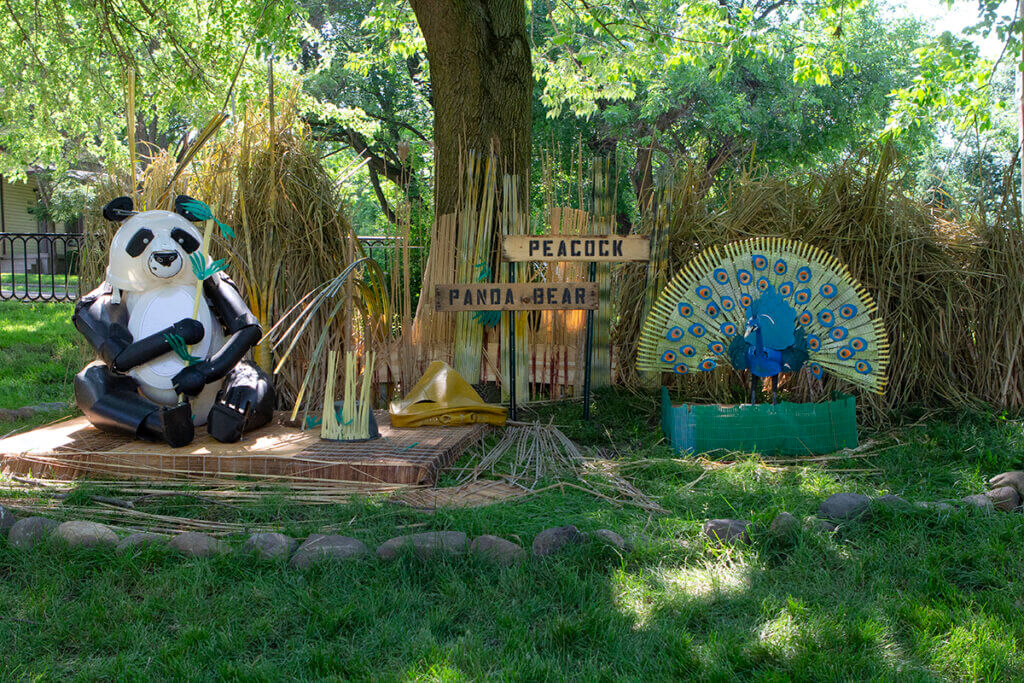 A panda and peacock are pictured in a scene all created from recycled materials