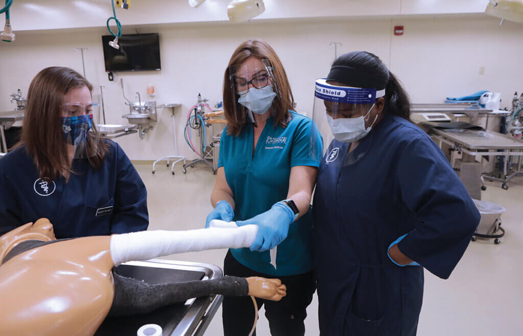 Dr. Inoue shows how to properly wrap a dog's leg using an animal model as students look on