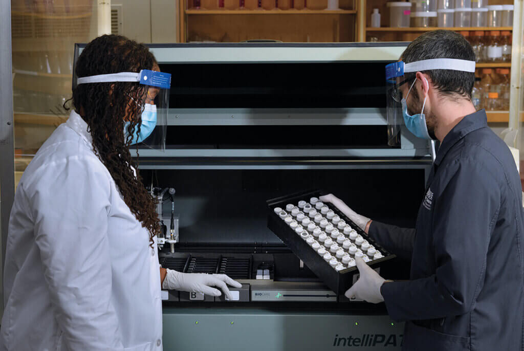 Dr. Lyle looks on as Victor handles samples in the Histology Research Laboratory